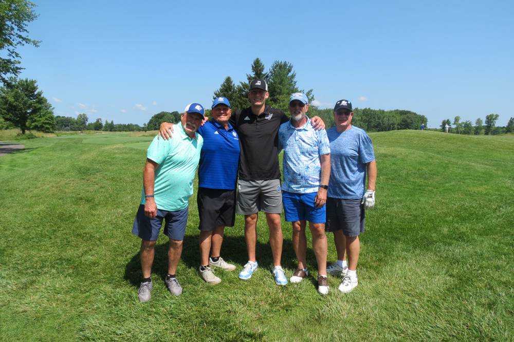 Five football alums standing on the golf course.